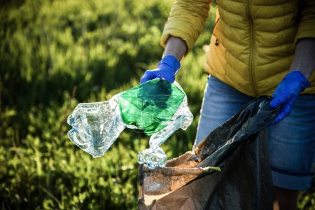 Téléchargez les photos : Bénévole ramassant des déchets en plastique Jour de la Terre - en image libre de droit