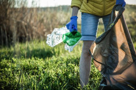 Téléchargez les photos : Bénévole ramassant des déchets en plastique Jour de la Terre - en image libre de droit