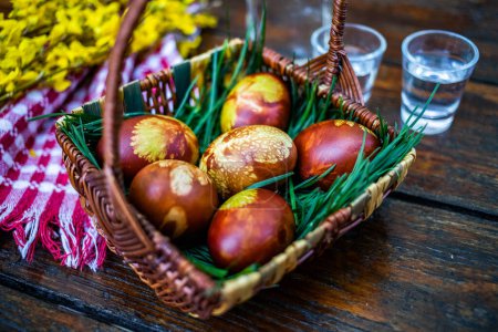 Téléchargez les photos : Oeufs de Pâques traditionnels dans un panier peint par ébullition dans des feuilles d'oignon rouge et à l'aide de feuilles - nourriture biologique - en image libre de droit