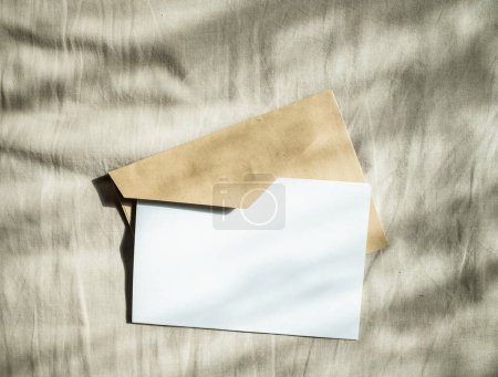 Foto de Tarjeta de felicitación en blanco invitación maqueta con sobre de papel artesanal composición de naturaleza muerta femenina - Imagen libre de derechos
