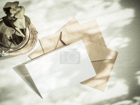 Foto de Tarjeta de felicitación en blanco invitación maqueta con sobre de papel artesanal composición de naturaleza muerta femenina - Imagen libre de derechos