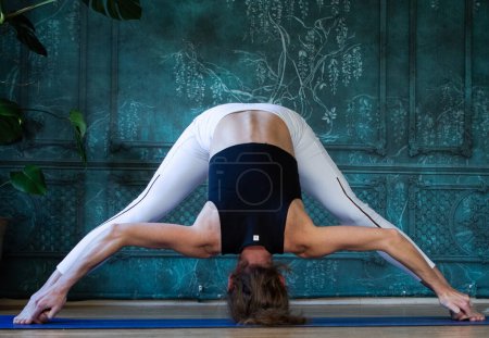 Téléchargez les photos : Femme faisant du yoga contre un mur vert - en image libre de droit