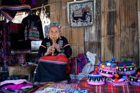 Foto de CHIANG MAI TAILANDIA - FEBRERO, 2019: Mujer de la tribu Hill vendiendo sus bienes en la aldea ecológica Baan Tong Luang cerca de Chiangmai, Tailandia - Imagen libre de derechos