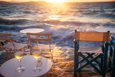 Téléchargez les photos : Verres à vin blanc au bord de la mer au coucher du soleil fond de voyage - en image libre de droit