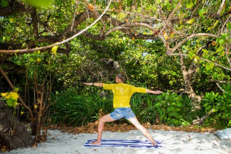 Téléchargez les photos : Femme faisant du yoga sur la plage tropicale - en image libre de droit
