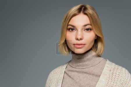 Photo for Portrait of blonde woman in turtleneck and cardigan looking at camera isolated on grey - Royalty Free Image
