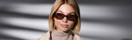 Photo for Stylish woman in warm turtleneck and sunglasses standing on abstract grey background, banner - Royalty Free Image