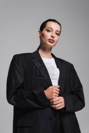 Téléchargez les photos : Vue à angle bas de la femme élégante en veste debout isolé sur gris - en image libre de droit