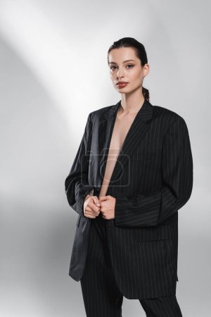 Photo for Trendy woman in striped jacket looking at camera on abstract grey background - Royalty Free Image