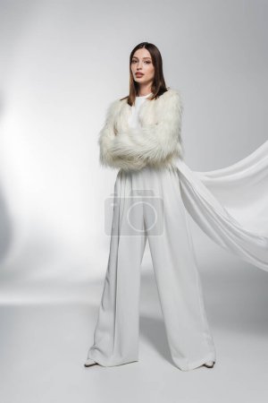 Photo for Woman in white clothes and faux fur jacket with clothing posing on abstract grey background - Royalty Free Image