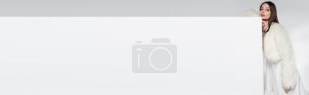 Téléchargez les photos : Jolie jeune femme en fausse fourrure blanche appuyée sur cube tout en posant sur gris, bannière - en image libre de droit