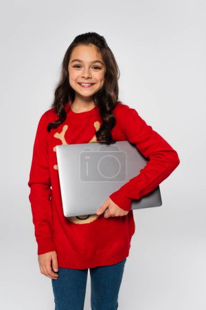 happy child in red Christmas sweater holding laptop isolated on grey