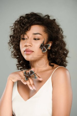 young african american woman with butterflies on hand and face isolated on grey