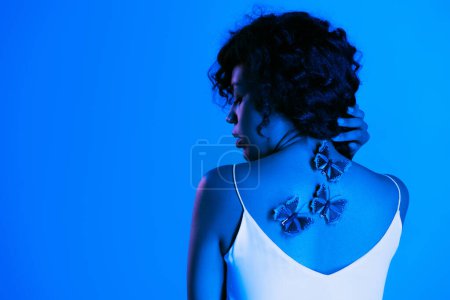 young african american woman with butterflies on back posing isolated on bright blue 
