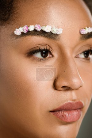 close up view of pretty african american woman with flowers on eyebrows