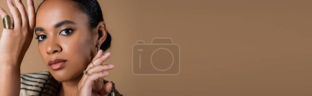 Téléchargez les photos : Femme afro-américaine avec des bagues dorées sur les doigts geste isolé sur beige, bannière - en image libre de droit