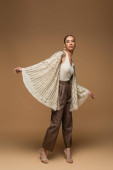 full length of young african american woman in golden jewelry and shawl posing on beige  Sweatshirt #620708274