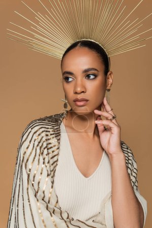 brunette african american woman in shawl and golden crown posing isolated on beige 