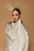 confident african american woman in shiny shawl and golden crown looking at camera isolated on beige  Sweatshirt #620708444