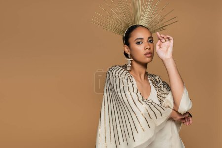confident african american woman in shiny shawl and golden crown looking at camera while posing isolated on beige  mug #620708454