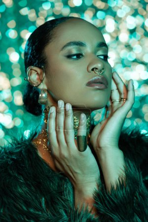 african american woman in trendy faux fur jacket and gold on neck on shiny blue background 