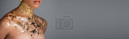 Téléchargez les photos : Vue recadrée d'une femme afro-américaine avec une feuille d'or sur le cou et les épaules isolées sur le gris, bannière - en image libre de droit