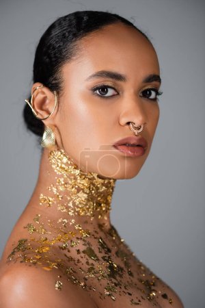 Portrait of african american woman with golden foil on chest looking at camera isolated on grey  magic mug #620709172