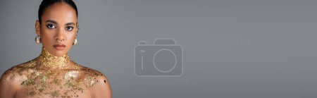 Téléchargez les photos : Jeune femme afro-américaine avec feuille d'or et accessoires isolés sur gris, bannière - en image libre de droit