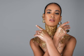 Trendy african american model with golden foil on body looking at camera isolated on grey  puzzle #620709550