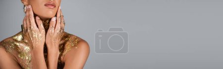 Cropped view of woman with golden foil on hands and chest touching face isolated on grey, banner  mug #620709604