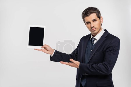 Photo for Businessman in suit holding digital tablet with blank screen isolated on grey - Royalty Free Image
