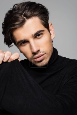 Photo for Portrait of good looking man in black turtleneck looking at camera isolated on grey - Royalty Free Image