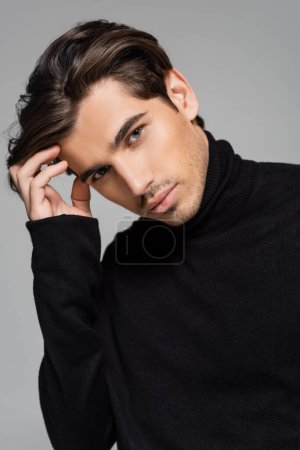 portrait of good looking man with blue eyes posing in black turtleneck isolated on grey