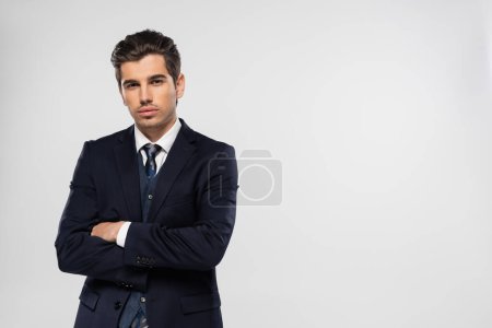 Foto de Hombre de negocios en traje mirando a la cámara mientras posa con los brazos cruzados aislados en gris - Imagen libre de derechos