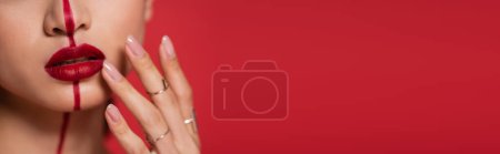 Photo for Cropped view of woman with makeup touching bright lips isolated on red, banner - Royalty Free Image