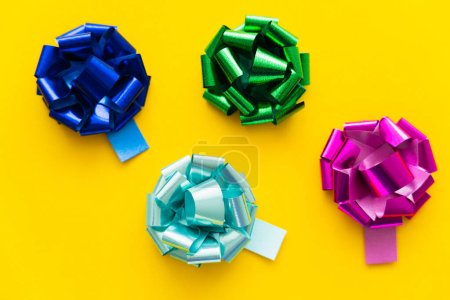 Top view of colorful gift bows on yellow background 
