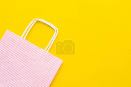 Top view of striped shopping bag on yellow background 