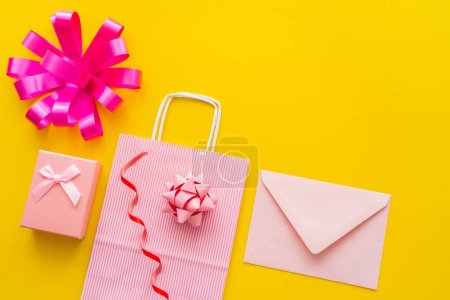 Photo for Top view of shopping bag near gift box and envelope on yellow background - Royalty Free Image