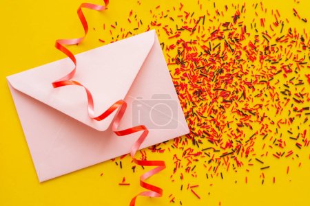 Photo for Top view of envelope and serpentine near sprinkles on yellow background - Royalty Free Image