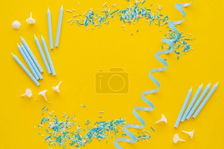 Téléchargez les photos : Vue du dessus des bougies près de la serpentine bleue et saupoudrer sur fond jaune - en image libre de droit