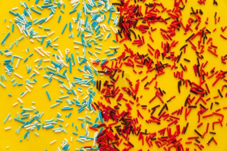 Top view of colorful sweet sprinkles on yellow background 