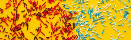 Top view of red and blue sprinkles on yellow background, banner 