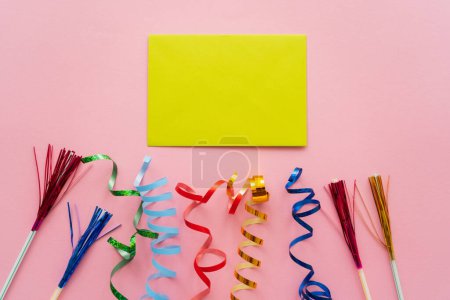 Top view of empty greeting card near drinking straws with tinsel and serpentine on pink background 