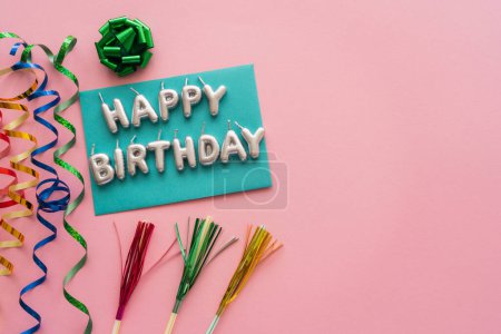 Photo for Top view of candles in shape of Happy Birthday lettering near serpentine and drinking straws on pink background - Royalty Free Image