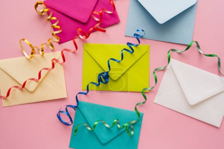 Top view of colorful serpentine on envelopes on pink background 