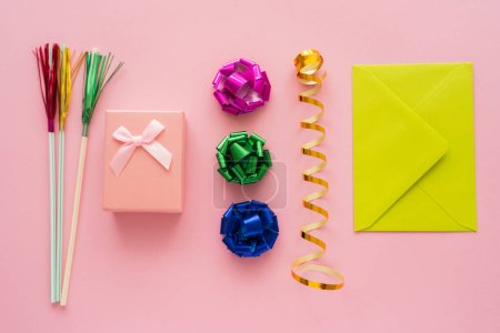 Top view of present near serpentine and envelope on pink background 