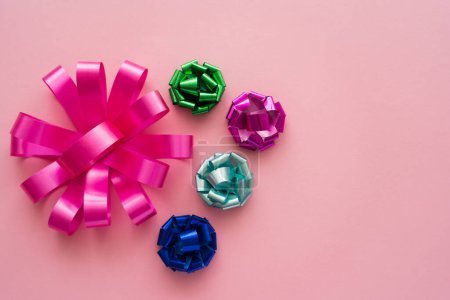 Top view of different colorful gift bows on pink background 