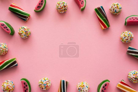 Widok z góry ramki z kolorowych cukierków na różowym tle 