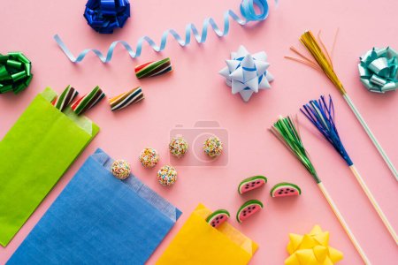 Photo for Top view of sweet candies near drinking straws and gift bows on pink background - Royalty Free Image