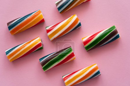 Foto de Puesta plana con caramelos rayados sobre fondo rosa - Imagen libre de derechos